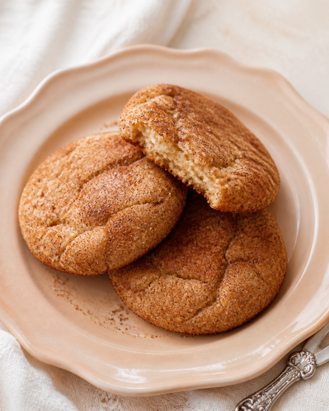 Three realistic cinnamon sugar snickerdoodle cookies on pale peach stoneware